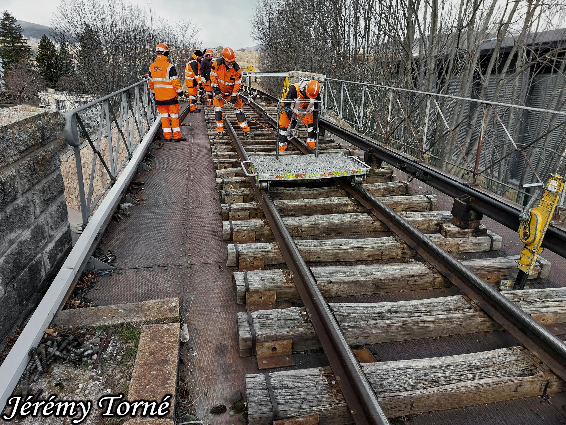 Cheminots de l infra vus de face avec la tirefonneuse remplacants des rails sur le pont metallique de bourg madame
